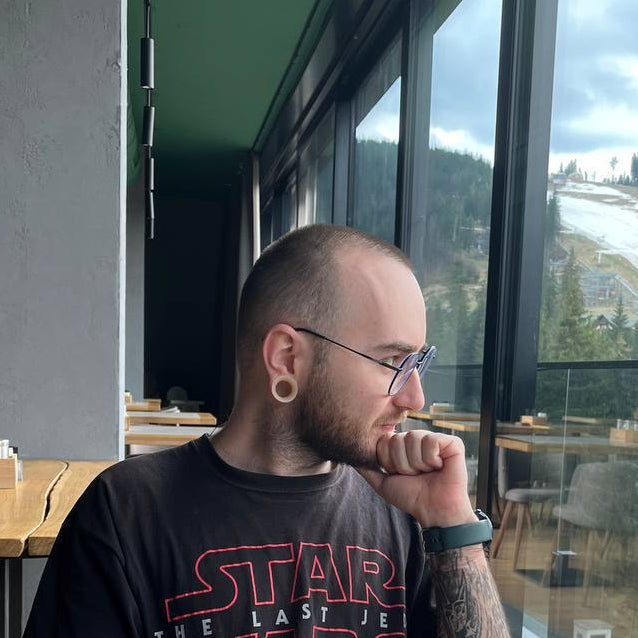 Person sitting at a table with a coffee cup, wearing a Star t-shirt, in a modern interior setting.
